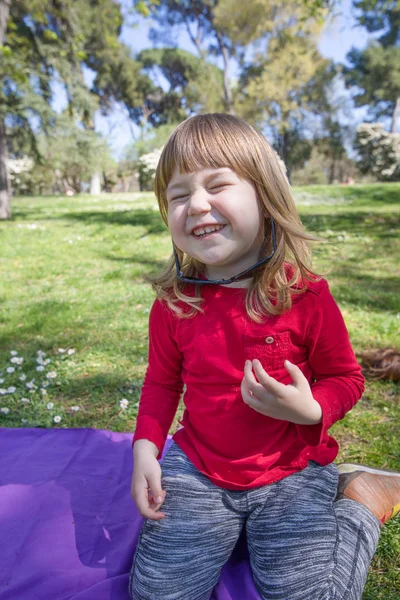 Смеющийся ребенок в парке играет со взрослыми солнцезащитными очками — стоковое фото