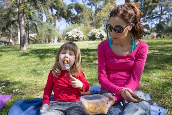 Μητέρα και παιδί κάθεται στο πάρκο τρώγοντας ζυμαρικά — Φωτογραφία Αρχείου