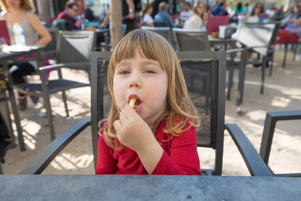 Portrait of child sitting in exterior bar eating cheese puff — Stock Photo, Image