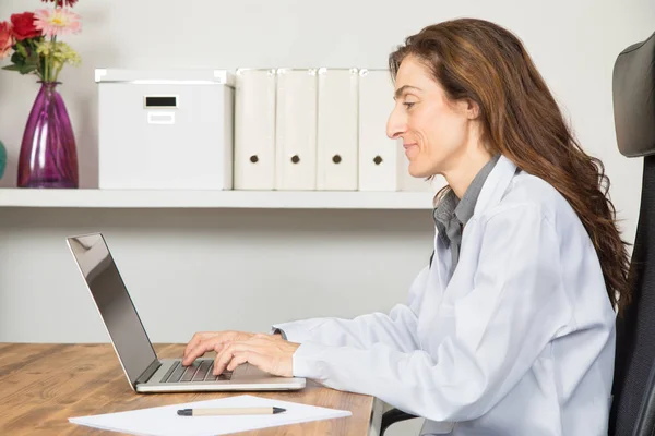Женщина-врач пользуется ноутбуком в офисе — стоковое фото