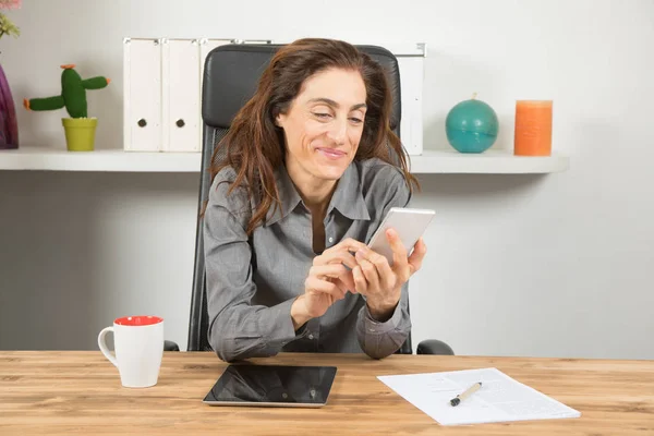 Улыбающаяся деловая женщина с мобильным телефоном и планшетом — стоковое фото