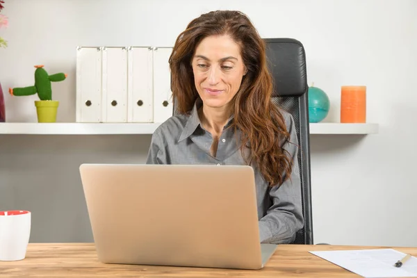 İşyerinde dizüstü bilgisayar kullanan kadın — Stok fotoğraf