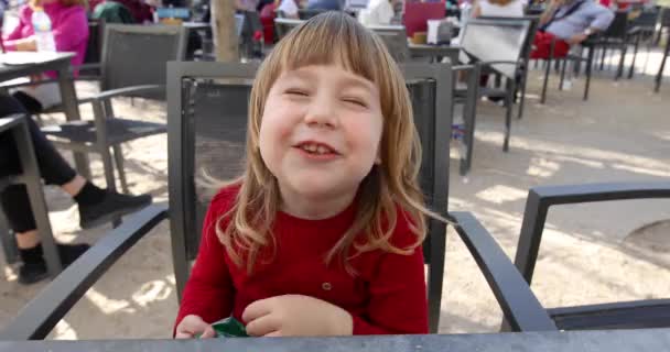 Ребенок сидит в кафе на террасе и ест слоеный сыр — стоковое видео