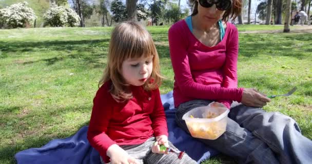 Mor och barn äta pasta i park — Stockvideo