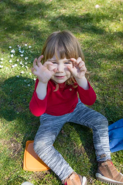 Dítě sedí na trávě škádlení s rukama v očích — Stock fotografie