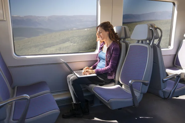 Visão lateral da mulher em trem digitando no computador portátil — Fotografia de Stock