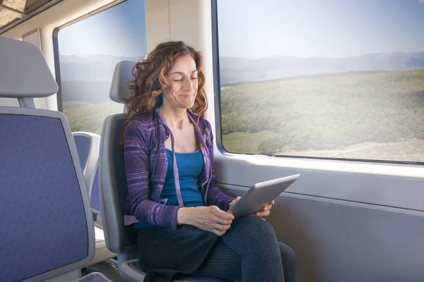 Mulher sorridente no trem leitura tablet digital — Fotografia de Stock