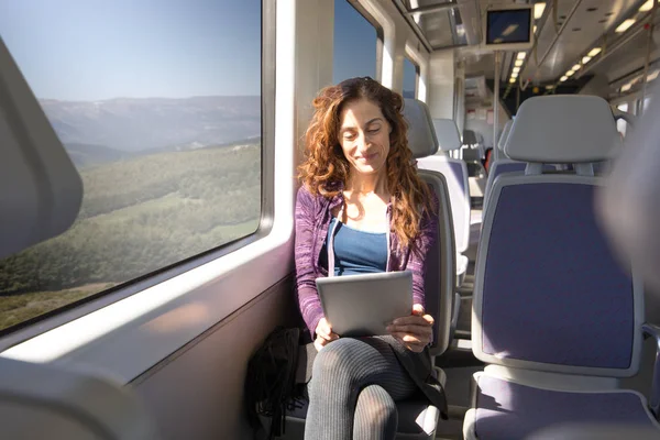 woman in train watching digital tablet happy face