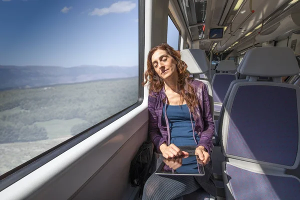 Mulher em trem dormindo com tablet digital nas mãos — Fotografia de Stock