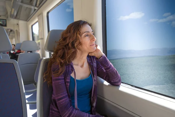 Mulher sentada no trem olhando pela janela — Fotografia de Stock