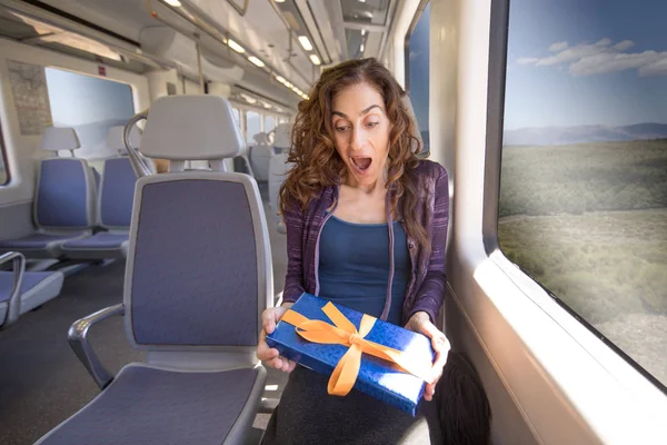 Mulher sentada no trem surpreso com presente — Fotografia de Stock