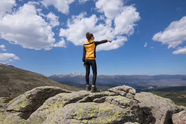 Indietro donna sulla cima della montagna che punta con mano — Foto Stock