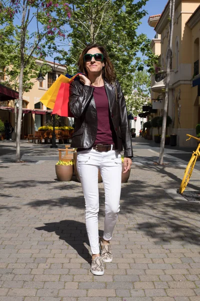Donna sorridente che cammina con le borse della spesa in strada — Foto Stock