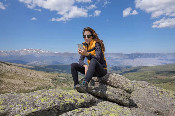 Frau benutzt Handy auf Berggipfel — Stockfoto