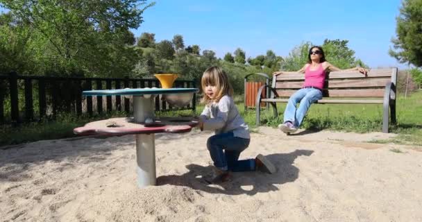 Child playing with sand and mother resting — Stock Video