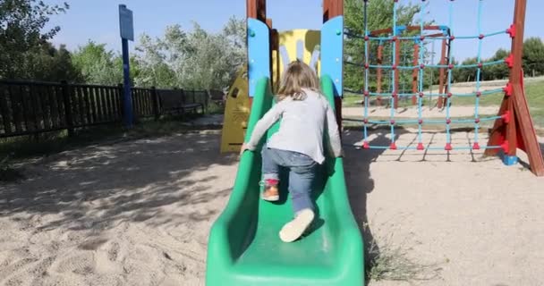 Dziecko stara się wspinać slajdów od tyłu — Wideo stockowe