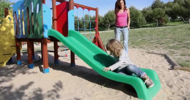 Child trying to climb slide with mother — Stock Video