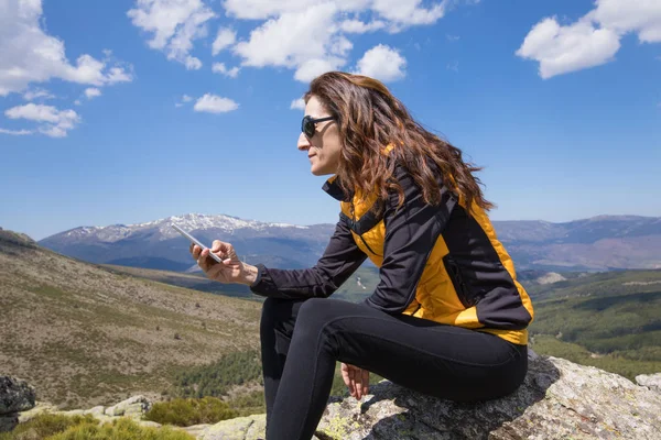 Sida kvinna att skriva mobila på toppen av berget — Stockfoto