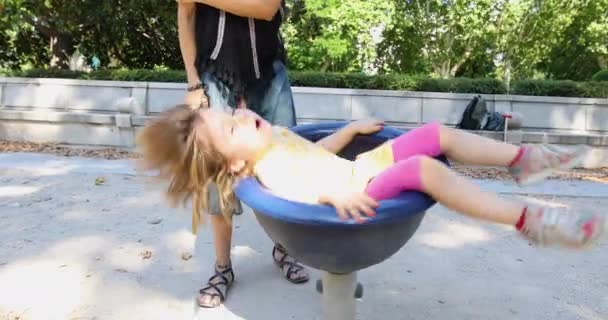 Glückliches kleines Mädchen dreht sich auf Spielplatz-Stuhl — Stockvideo