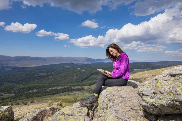Glückliche Frau sitzt im Tablet auf dem Gipfel des Berges — Stockfoto