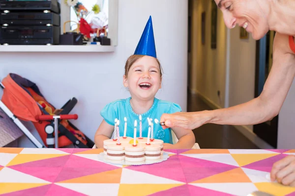 Criancinha rindo e mulher acendendo velas no bolo de aniversário — Fotografia de Stock