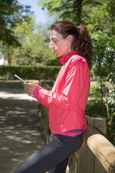 Mulher usando smartphone em passarela de madeira — Fotografia de Stock