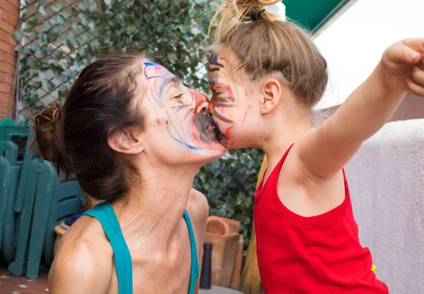 Niña y madre con cara pintada besándose —  Fotos de Stock