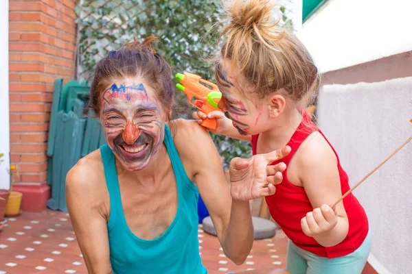 Mãe e filha com rosto pintado rindo no terraço — Fotografia de Stock