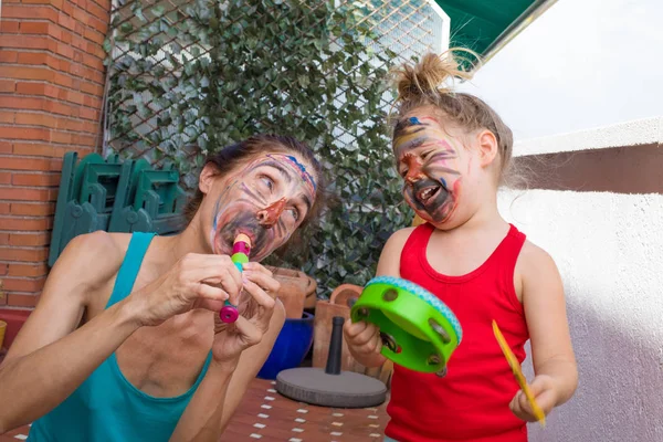 Mutter und kleines Kind mit gemaltem Gesicht beim Musizieren — Stockfoto