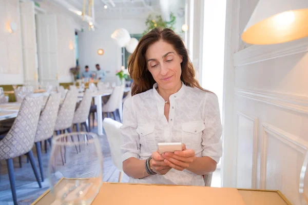 Mujer en restaurante usando teléfono móvil — Foto de Stock