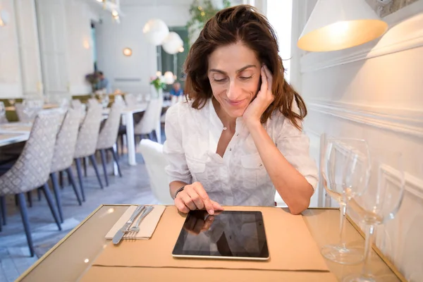 Mujer en restaurante usando tableta con pantalla en blanco — Foto de Stock