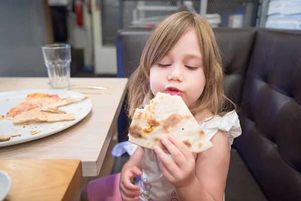 Menina comendo pizza com a mão no restaurante — Fotografia de Stock