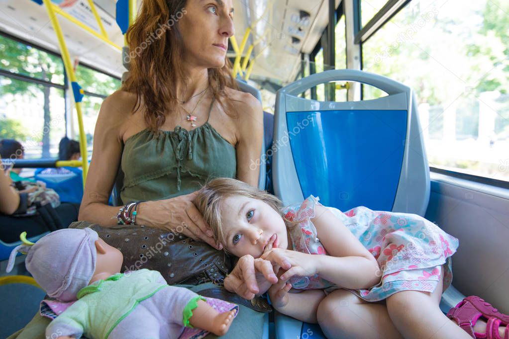 little girl lying on mother legs on the bus