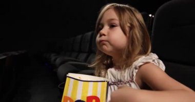 küçük çocuk sinemada patlamış mısır yemek