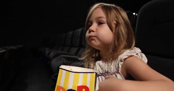 Маленький ребенок ест попкорн в кинотеатре — стоковое видео