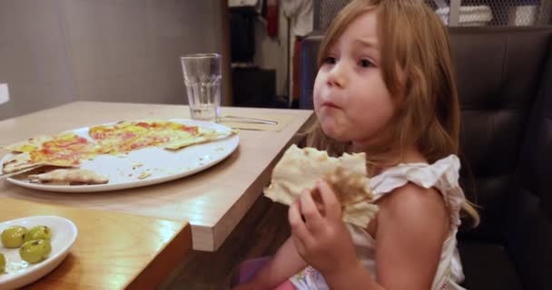Маленькая девочка в ресторане ест пиццу и танцует — стоковое видео