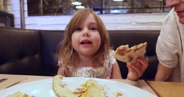 Little girl in restaurant speaking and eating pizza — Stock Video