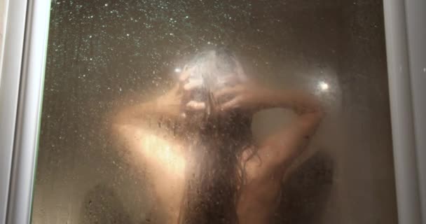 Mujer lavándose el pelo detrás de vidrio — Vídeo de stock