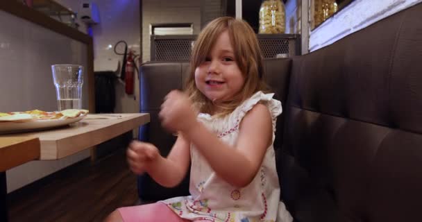 Little girl singing and playing with hands in restaurant — Stock Video