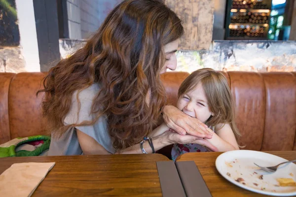 Küçük kız anne elinde Restoran ısırma — Stok fotoğraf