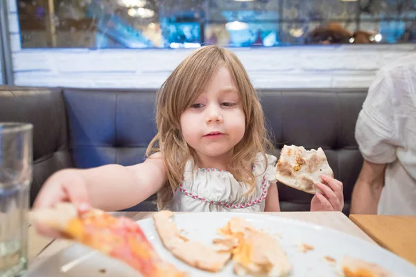 Menina tomando pedaço de pizza com a mão no restaurante — Fotografia de Stock