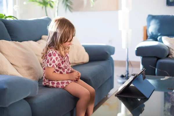 Menina assistindo tablet na sala de estar ensolarada — Fotografia de Stock