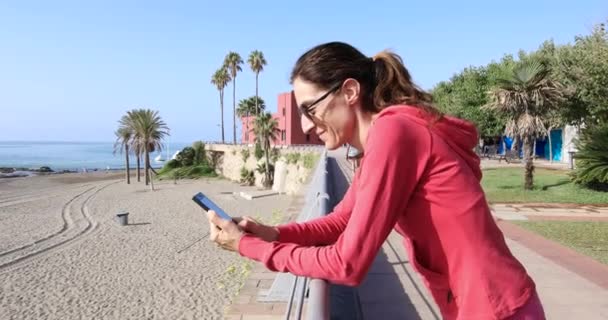 Vrouw in zee kant promenade kijken naar mobiel — Stockvideo