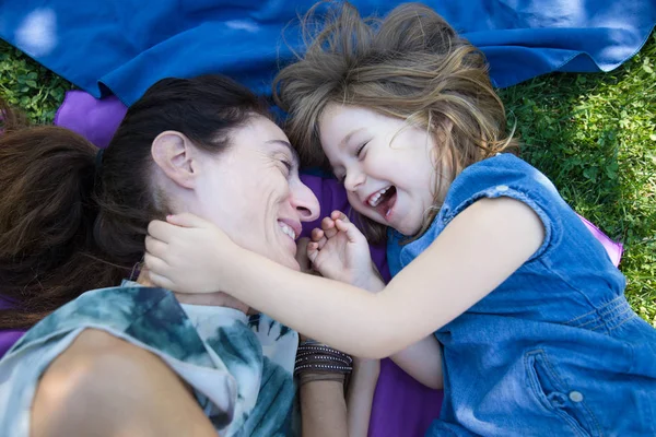 Menina e mãe rindo deitado no parque — Fotografia de Stock