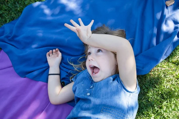 Девушка лежит в парке смеясь и дразня — стоковое фото