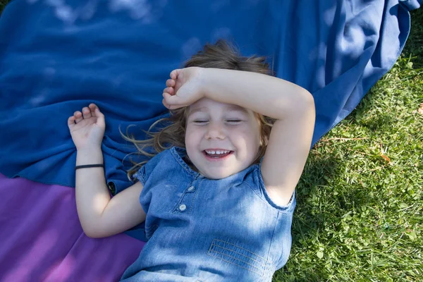 Menina deitada no parque rindo com os olhos fechados — Fotografia de Stock