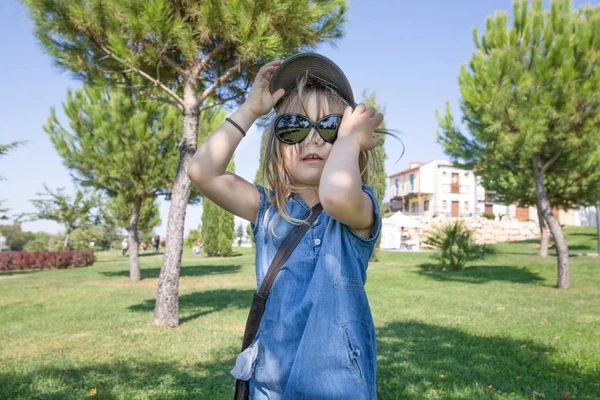 Flicka i park med stora solglasögon och mössa inne — Stockfoto