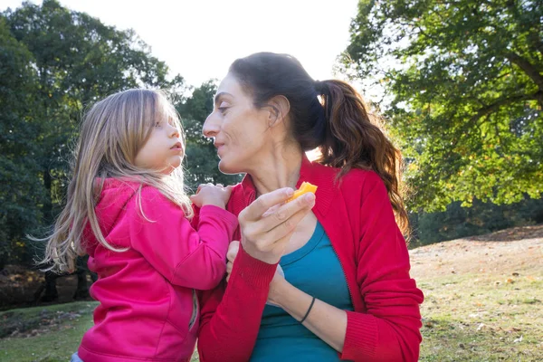 Matka a litlle dítě v přírodě jíst broskev — Stock fotografie