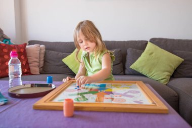 Yaz aylarında evde parchis oyun oynayan küçük çocuk