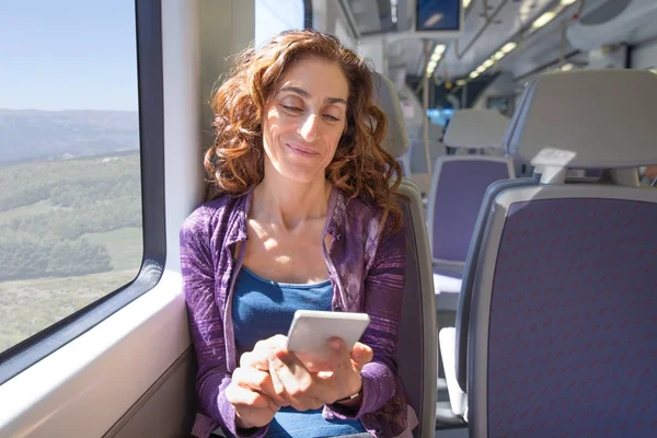 Lächelnde Frau im Zug berührt Smartphone — Stockfoto